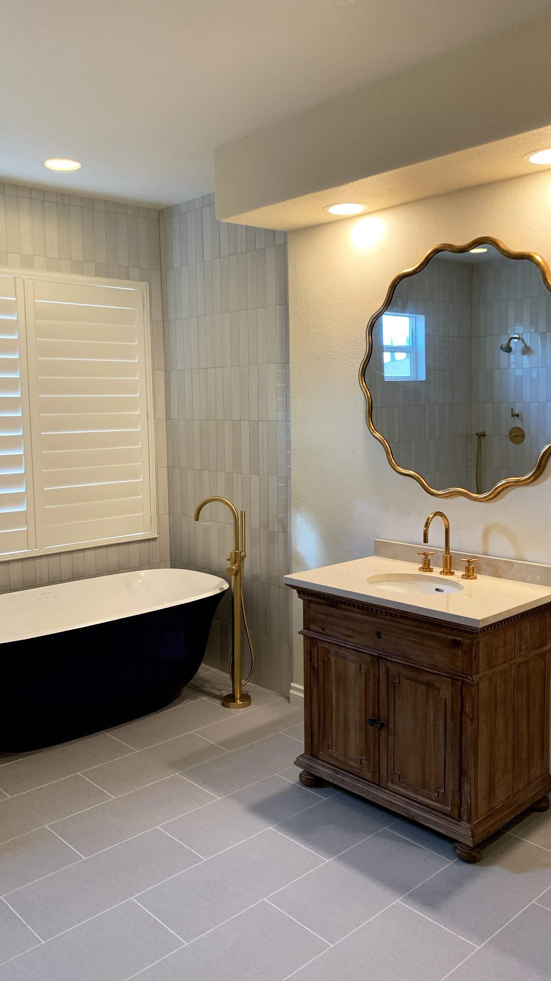 Completed bathroom with freestanding tub, custom shower, vanity, tile, and coordinated brass fixtures